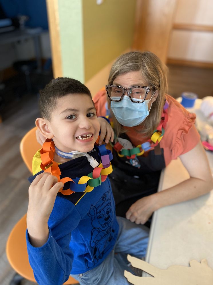 Dominic making construction paper chains with Ziggy's Art Bus specialist Vicky.